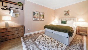 A bedroom with a bed, bedside tables, a dresser, a mirror, and two framed posters on the wall. - The Earl's Court Wonder - Adorable 1bdr Flat With Terrace (London)