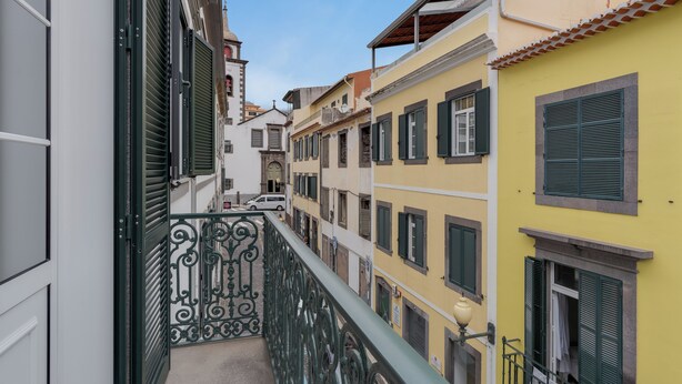 A narrow street with buildings on either side, featuring balconies with metal railings and shutters. - Funchal City Nest III (Funchal)