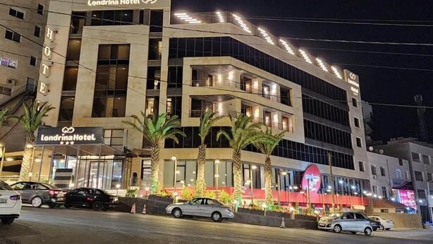 El exterior del Hotel Londrina de noche, con un diseño arquitectónico moderno que incluye varios balcones y un llamativo letrero del hotel.