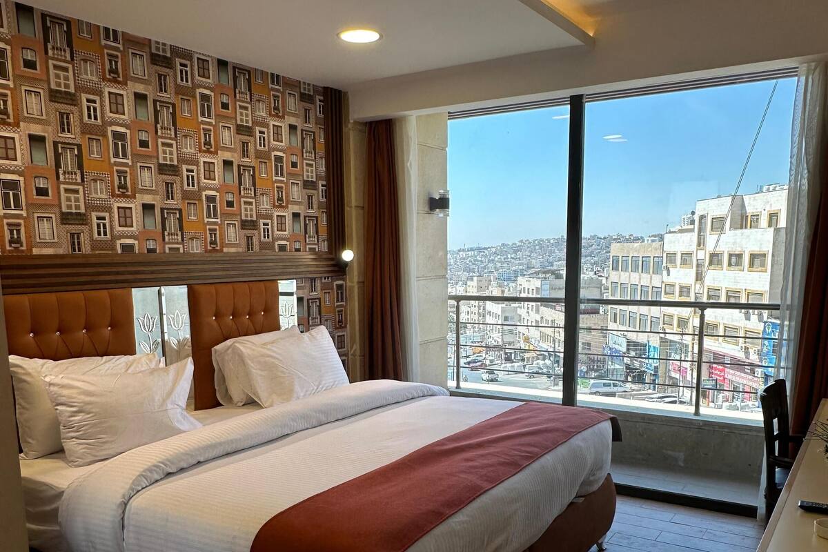 A hotel room with a large bed, a view of the city, and a modern design.