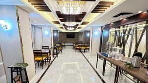 Un vestíbulo de hotel con suelo de mármol, muebles de madera, una araña y una larga mesa con servicios.