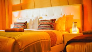 Ein Hotelzimmer mit einem großen Bett, mehreren Kissen, einem Nachttisch mit Lampe und einer Decke.