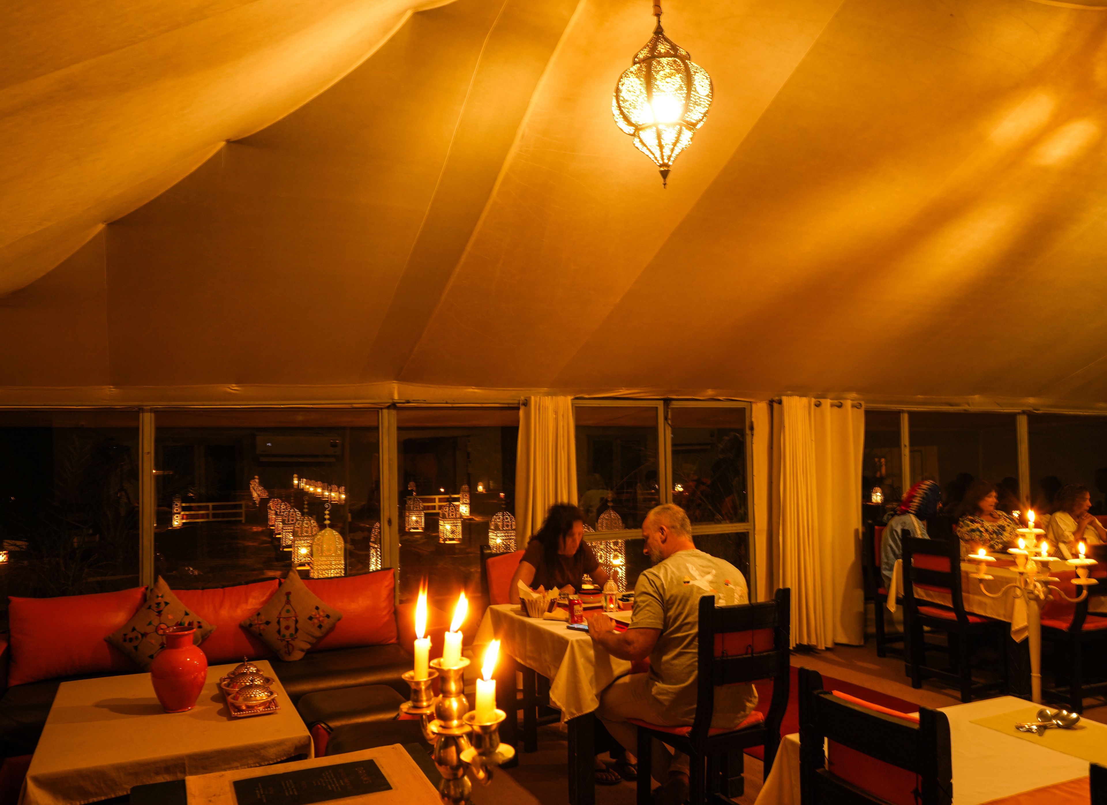 Un área de comedor con toldo, mesas, velas y una araña.