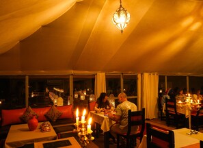 A tented dining area with tables, candles, and a chandelier. - Dounia Luxury Camp (Rissani)