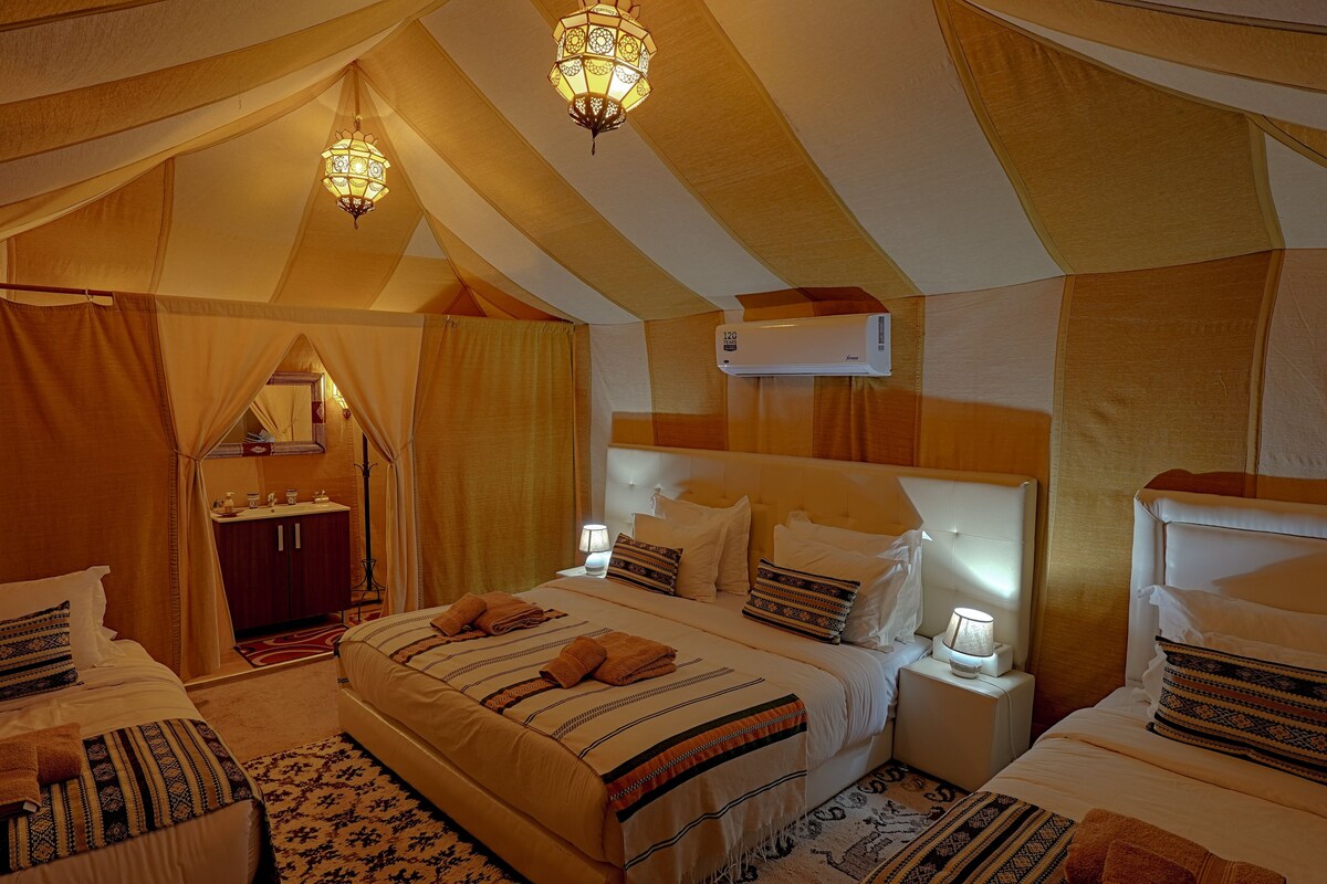 A tent-style room with two beds, a vanity, and a hanging light fixture.
