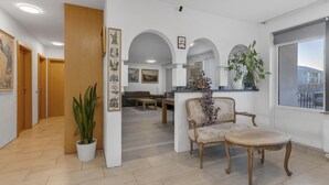 A spacious living area with a wooden floor, a dining table, a sofa, and a potted plant.