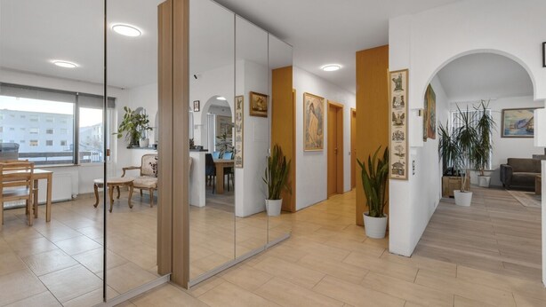 A modern interior with a dining area, a reception desk, and a hallway with framed artwork.