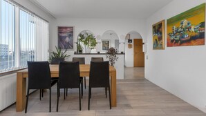 A modern dining area with a wooden table and black chairs, white walls, and artwork.
