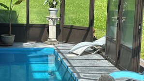 Ein Schwimmbecken mit Steinbord, einer weißen Statue und einem Blumentopf.