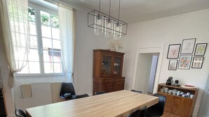Ein Essbereich mit Holztisch und schwarzen Stühlen, einem Holzschrank und einer Heizung.