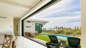 Un intérieur moderne avec une grande fenêtre donnant sur une piscine et un espace verdoyant.