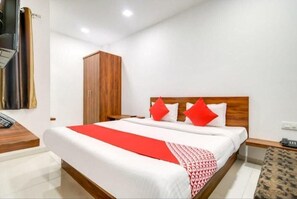 A hotel room with a large bed, wooden headboard, and a wardrobe. - Hotel Apple Grand (Indore)