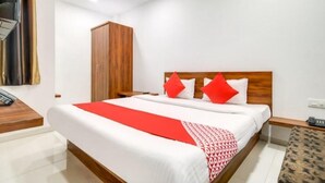 A hotel room with a large bed, wooden headboard, and a wardrobe. - Hotel Apple  (Indore)