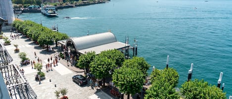 A waterfront promenade with a covered walkway, trees, and a view of the lake.