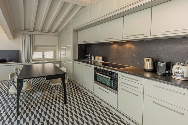 A modern kitchen with a black countertop, stainless steel appliances, and a checkered floor.