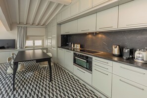 A modern kitchen with a black countertop, stainless steel appliances, and a checkered floor. - Rebecca Suite Florence (Firenze)