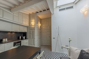 Een moderne keuken met witte kasten, een zwart aanrecht en een eethoek met een geruit vloertje.