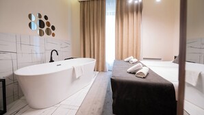 Un bagno moderno con una vasca freestanding, una panca lunga con asciugamani e un grande specchio con cornice circolare.