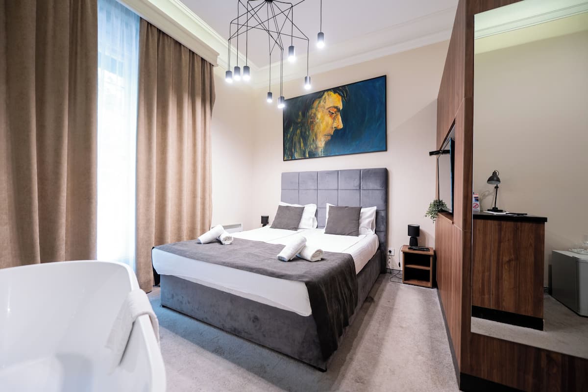 Ein modernes Schlafzimmer mit einem großen Bett, einer weißen Badewanne und einem Holztisch.
