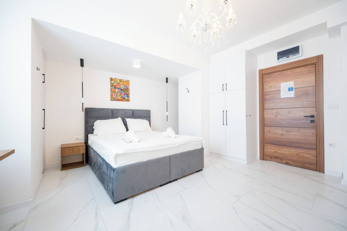Ein modernes Schlafzimmer mit einem großen Bett, einem Holzschrank und einer Kronleuchter.