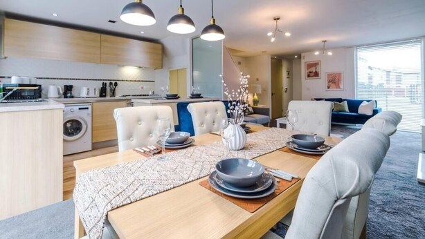 A modern kitchen with a dining area, including a table set for four with plates, bowls, and cutlery.
