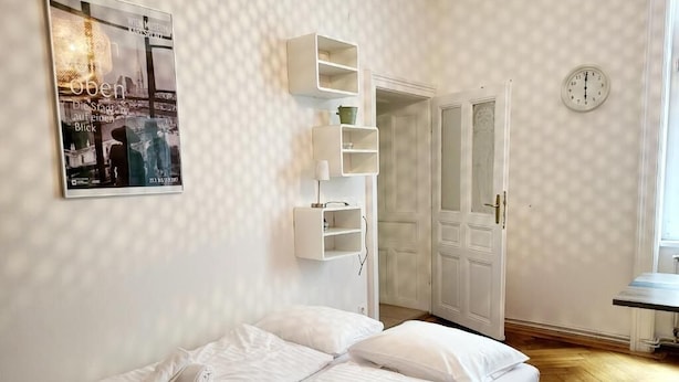 A bedroom with a bed, white walls, a framed picture, a clock, and a door. - Wipplinger Home Apartment Vienna (Vienna)
