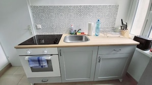 A kitchen with a stove, sink, and countertop. There is a window providing natural light. - Wipplinger Home Apartment Vienna (Vienna)