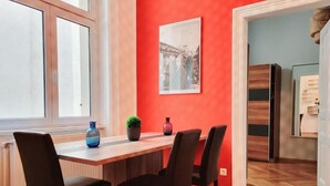 A dining area with a wooden table and four chairs, a red wall, and a framed picture. - Wipplinger Home Apartment Vienna (Vienna)