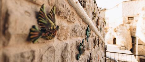 Una pared de piedra adornada con mariposas metálicas decorativas y un tubo de metal.