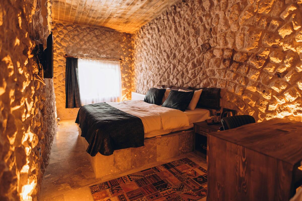 Ein Schlafzimmer mit Steinwänden, einem Bett, einem Nachttisch und einem Holzschrank.
