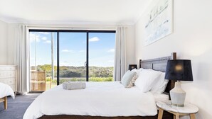Un dormitorio con una cama grande, una mesita de noche, una lámpara y vistas al exterior.
