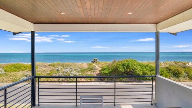 Un balcón techado con vistas al mar y la vegetación de la playa.