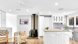 A modern kitchen with white cabinets, a central island, and a built-in stove. - Natuna Lakeside Retreat (Budgewoi)