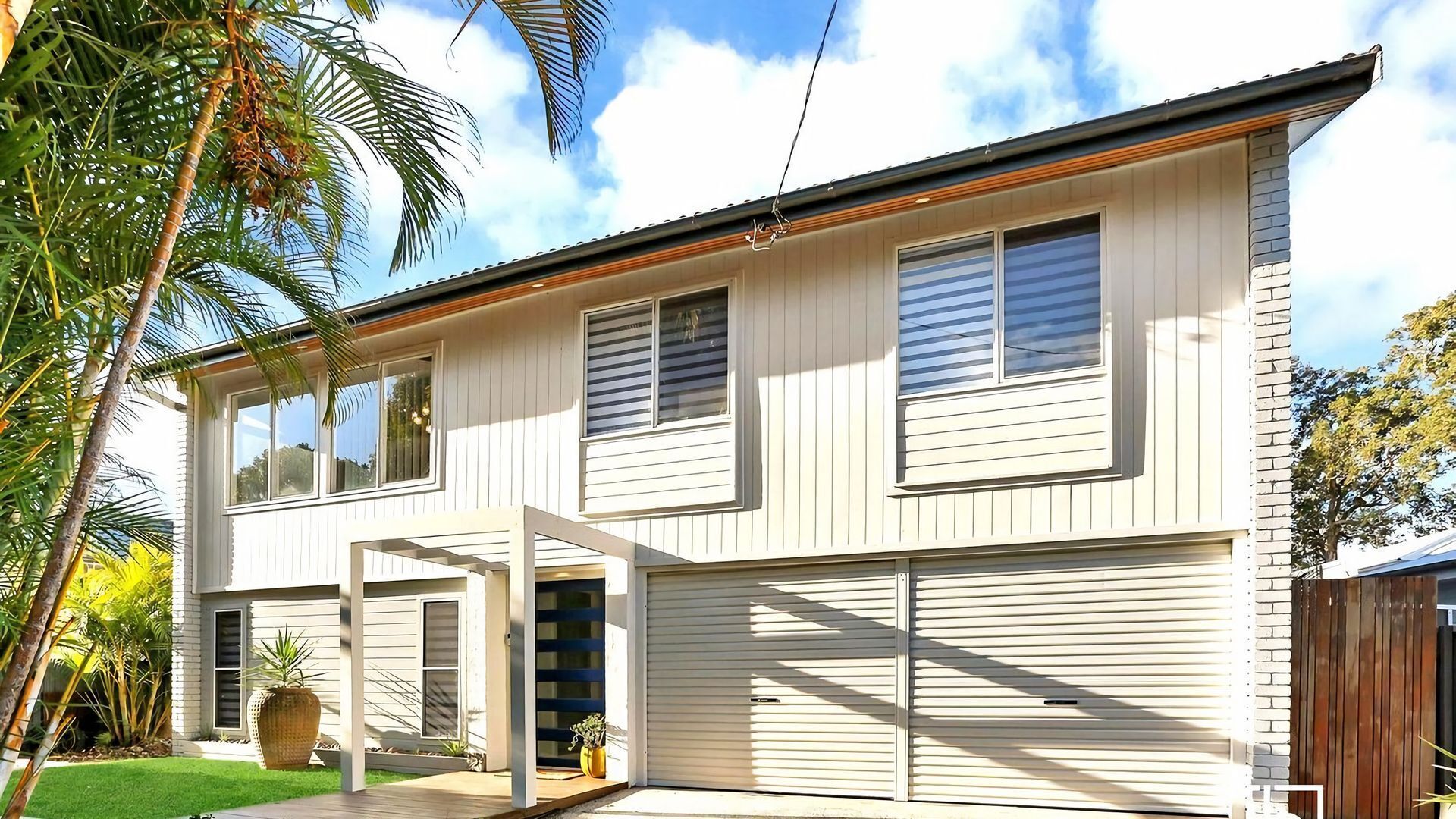 A two-story house with a garage, a covered patio, and a well-maintained lawn.