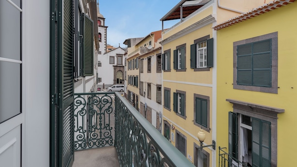 A narrow street with buildings on either side, featuring balconies with metal railings and shutters. - Funchal City Nest III (Funchal)