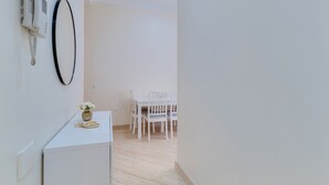 A clean, minimalist room with a white desk, a telephone, and a vase with flowers. - Funchal City Nest III (Funchal)