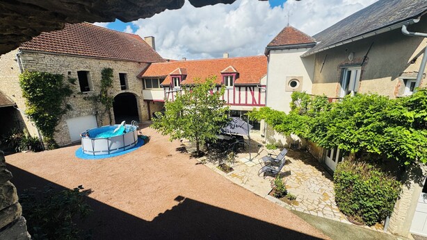 A courtyard with a swimming pool, stone buildings, and a red-tiled roof.