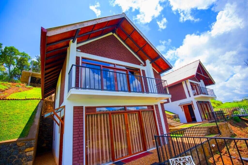 A modern two-story house with a red and white exterior, large windows, and a balcony.