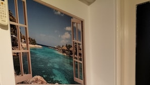 A white cabinet with two drawers and a window above it displaying a beach scene.