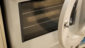 A white oven with a front door, a control panel with dials, and a stainless steel range hood.