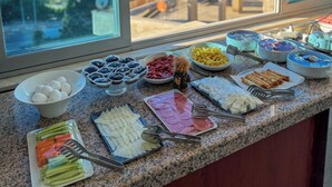 A buffet spread with various food items and a scenic view of the ocean and trees through large windows. - Deluxe Ersoy Hotel (Antalya)