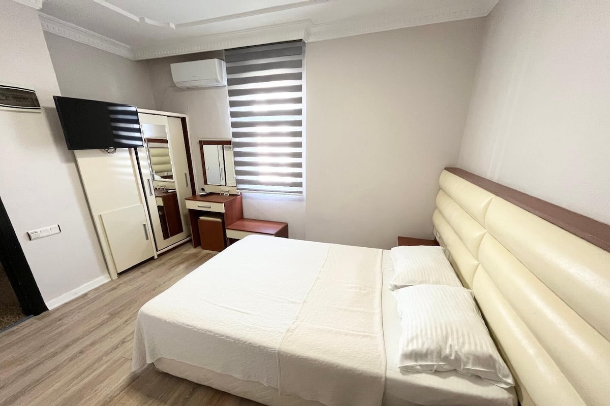 Une chambre d’hôtel équipée d’un lit, d’un bureau, d’une chaise, d’une armoire et d’un téléviseur.