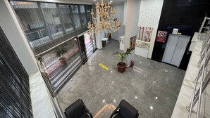 A spacious lobby with a chandelier, a reception desk, and a seating area with two chairs. - Deluxe Ersoy Hotel (Antalya)