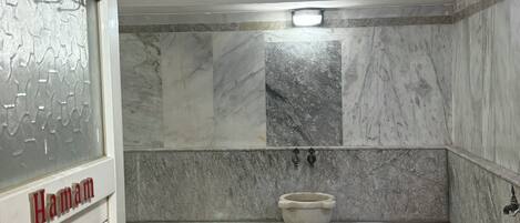 A bathroom with a marble floor, a sink, and a bathtub.