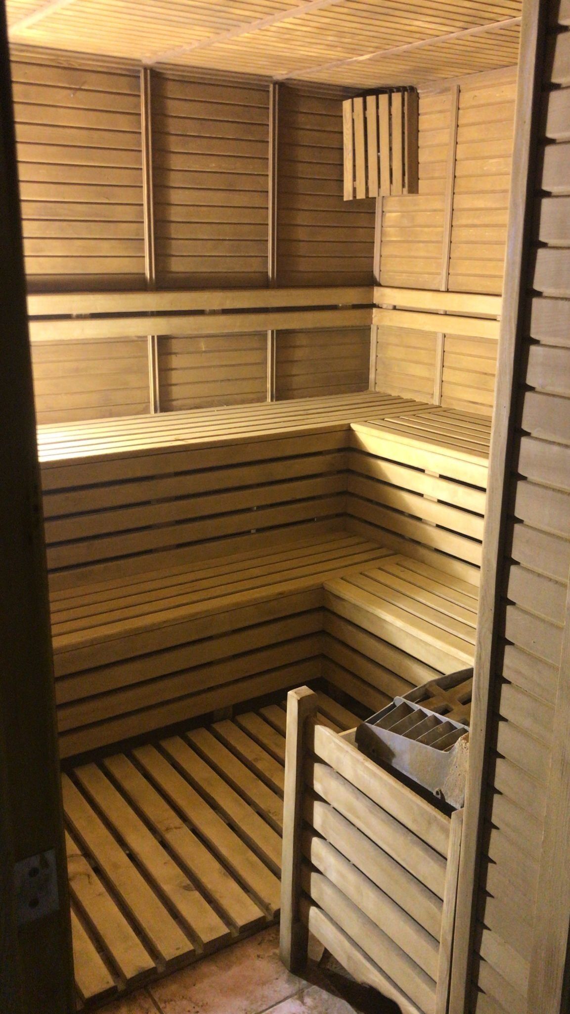 A sauna with wooden benches and a slatted floor.