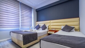A modern hotel room with two beds, a large window with blinds, a headboard with storage, and a wooden floor. - Deluxe Ersoy Hotel (Antalya)