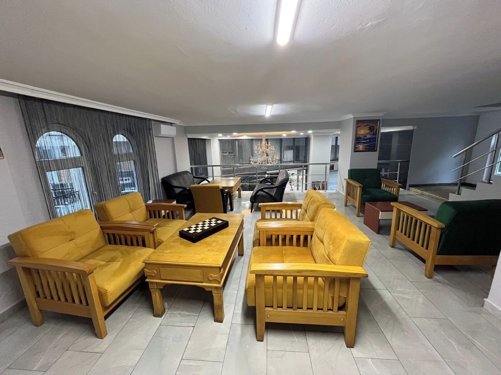 Amplia sala de estar con sofás amarillos, una mesa de centro de madera y un candelabro.
