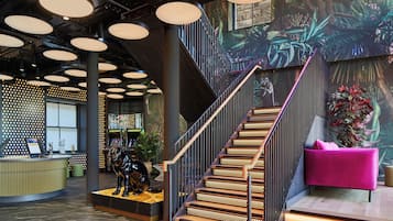 A modern interior with a staircase, a reception desk, and a vibrant mural.