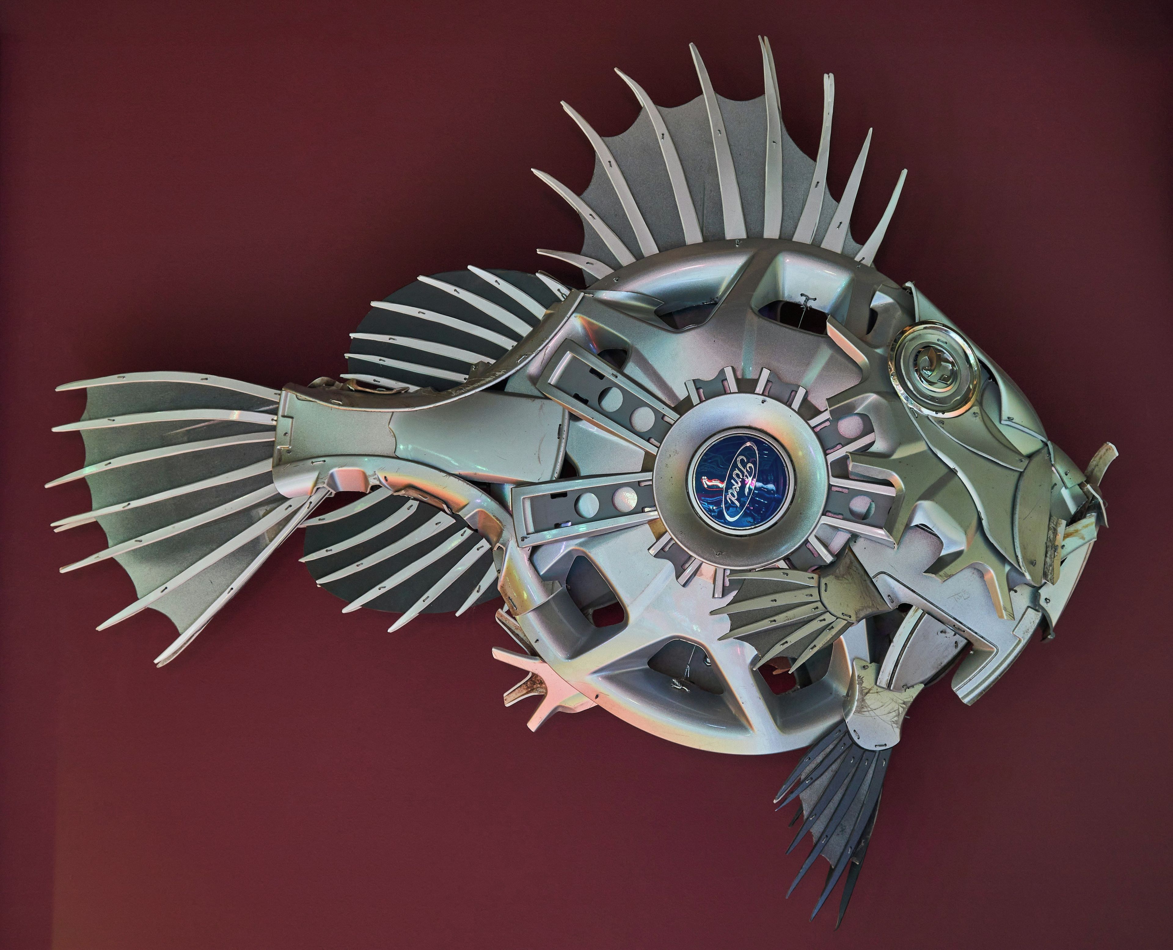 Une sculpture représentant un poisson, faite de métal, et ornée d’un emblème central.