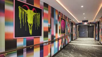 A hallway with colorful striped walls, a marble floor, and a sign indicating a gym.